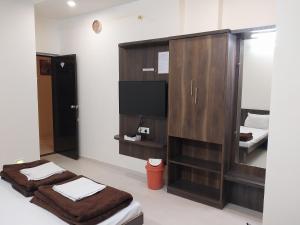 a room with two beds and a flat screen tv at Hotel Jawahar Palace in Bhusāwal