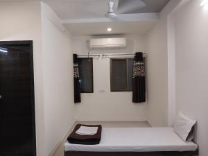 a white room with a bed and a window at Hotel Jawahar Palace in Bhusāwal