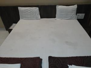 a large white bed with two pillows on it at Hotel Jawahar Palace in Bhusāwal +1 photo