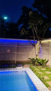 a swimming pool with a tree next to a wall at D 'Jambon Escape in Yogyakarta