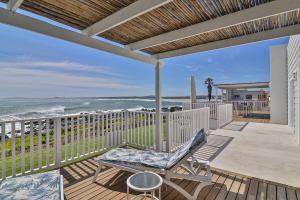 a porch with a chair and the beach at On the Rocks in Yzerfontein