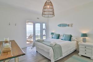 a bedroom with a bed with blue pillows and a table at On the Rocks in Yzerfontein