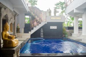 a swimming pool with a statue in front of a building at Kabera House 1 in Ubud