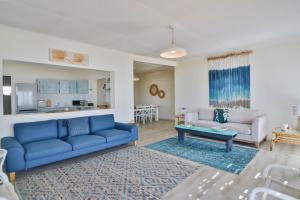 a living room with a blue couch and a table at On the Rocks in Yzerfontein