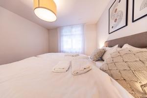 a white bedroom with two beds and a window at The R Apartment Hemmental in Schaffhausen