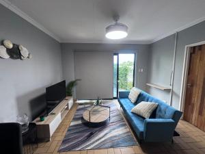 a living room with a blue couch and a tv at Forest and Ferns in Graskop