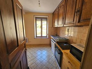a kitchen with wooden cabinets and a stove top oven at le flocon chaud in La Bresse