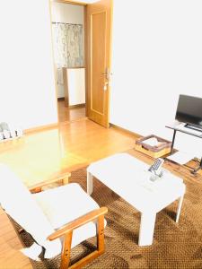 een woonkamer met twee witte tafels en een piano bij れのん in Okazaki