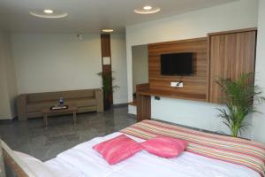 a bedroom with a bed with two pink pillows on it at HOTEL RAJPATH Inn in Mahesāna