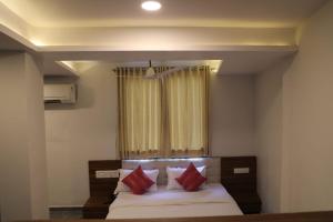 a bedroom with a bed with red pillows and a window at HOTEL RAJPATH Inn in Mahesāna