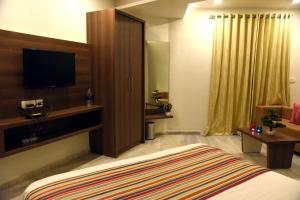 a hotel room with a bed and a flat screen tv at HOTEL RAJPATH Inn in Mahesāna +13 photos
