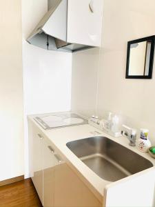 eine weiße Küche mit einer Spüle und einer Theke in der Unterkunft れのん in Okazaki