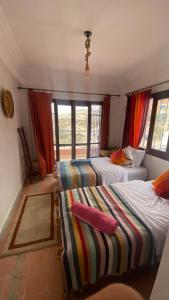 twee bedden in een kamer met ramen en een kamer bij Nova surf house in Tamraght Ou Fella +5 foto's