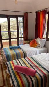 een slaapkamer met twee bedden met kleurrijke dekens erop bij Nova surf house in Tamraght Ou Fella