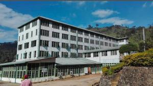 a large white building with a person standing in front of it at River cottage Demodara in Demodera
