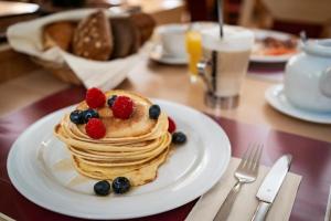 a white plate with pancakes and berries on a table at Hotel am Marschiertor by ANS in Aachen +54 photos
