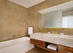 a bathroom with a tub and a sink and a mirror at The Ritz-Carlton, Herzliya in Herzliya +124 photos