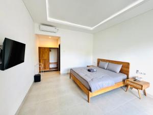 a bedroom with a bed and a flat screen tv at Chevana House Jimbaran in Jimbaran +16 photos
