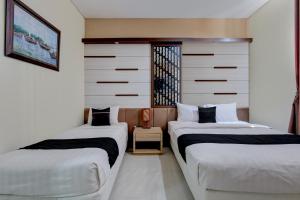 two beds sitting next to each other in a room at Collection O near Stadion Manahan formerly Graha Laweyan Solo in Bonorejo +26 photos