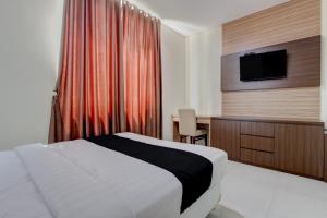 a bedroom with a bed and a desk and a television at Collection O near Stadion Manahan formerly Graha Laweyan Solo in Bonorejo