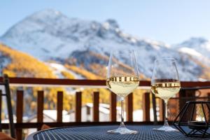 two glasses of white wine on a table with a view at Cornelia 1 Ski-In-Out Stunning Views & Sleeps 8 in Saas-Fee