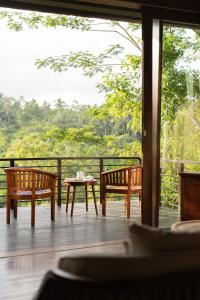 two benches and a table on a porch with a view at Villa Leona Ubud in Ubud