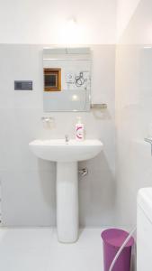 a white bathroom with a sink and a mirror at Isuru Homestay Pidurangala in Sigiriya