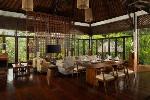 a dining room with a table and chairs and windows at Villa Leona Ubud in Ubud