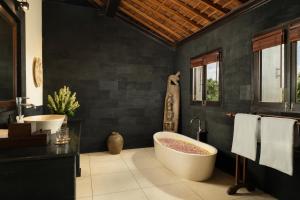 a bathroom with a large tub and a black wall at Villa Leona Ubud in Ubud +12 photos