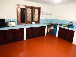 a kitchen with brown cabinets and a wooden floor at Tea Leaf Family Cottage in Bandarawela