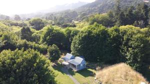 an aerial view of a blue house in the forest at Okuti Country Cottage, a private and peaceful retreat in Little River