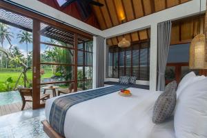 a bedroom with a large bed and a balcony at Bara Villa by GenuineHost in Tegalalang