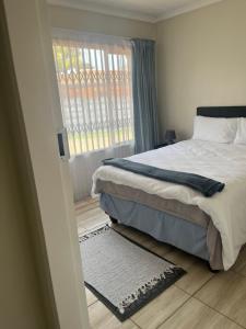 a bedroom with a bed and a window and a rug at Centurion Family House in Centurion