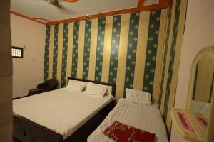 two beds in a small room with green wallpaper at Sabri Palace Ayodhya in Ayodhya