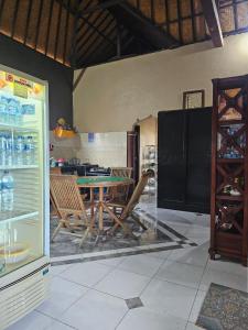 una sala da pranzo con tavolo, sedie e frigorifero di Ibu Ana Homestay a Tabanan
