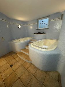 a bathroom with two tubs and a tv on the wall at Hotel Ai Pini in Vigo di Fassa +61 photos