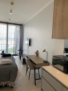 a bedroom with a bed and a desk and a kitchen at Ellipse Luxurious Tamarind Green Studio Experience in Midrand