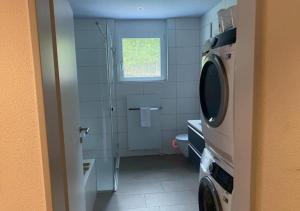 a bathroom with a shower and a washing machine at The R Apartment Adlisberg in Geroldswil
