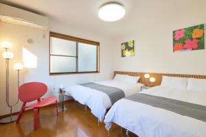 a bedroom with two beds and a red chair at Yotsuya Lantern - Private 3 stories house for family in Tokyo