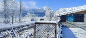 a building covered in snow with mountains in the background at Id villa cottage in Tangmarg +16 photos