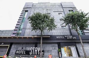 a hotel style building with two trees in front of it at The Stay Nangman Seongseo in Daegu