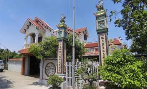 a building with a fence and a clock tower at Ecohost Hai Trung in Háº£i Háº­u