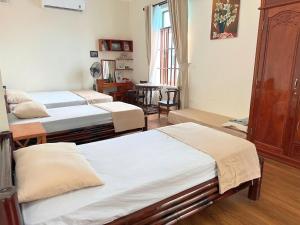 a room with three beds and a table with a window at Ecohost Hai Trung in Háº£i Háº­u