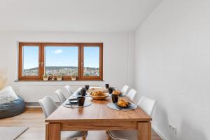 a dining room with a wooden table and white chairs at Business & Relax Suite - Panorama - 2 Schlafzimmer - Parkplatz in Sindelfingen
