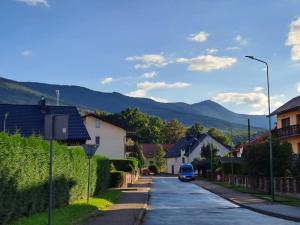 a blue van driving down a street with houses and mountains at Silver Apartament Kowary in Kowary