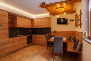 a kitchen with wooden cabinets and a table with chairs at Appartamenti Chalet Canedi in Peio