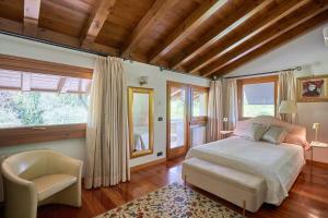 a bedroom with a bed and a chair and windows at Dream's hill in San Pietro di Feletto