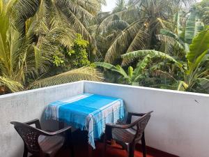 a table and two chairs on a balcony with palm trees at Chamila's place in Nikawatawana