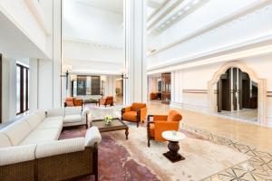a living room with a white couch and chairs at Grand Hotel De Djokja in Yogyakarta