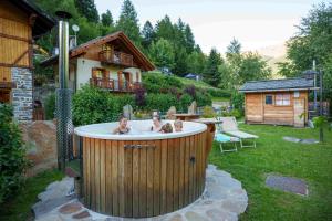 two people in a hot tub in a yard at Appartamenti Chalet Canedi in Peio +15 photos
